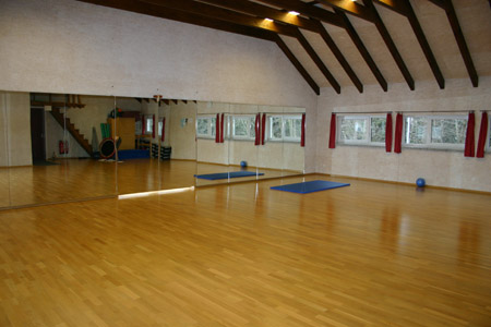 Heller Kursraum mit Parkettboden, Spiegelwand und Gymnastikmatten